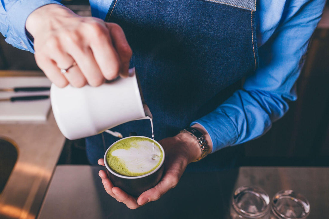 Barista batiendo matcha con chasen en la barra de una cafetería
